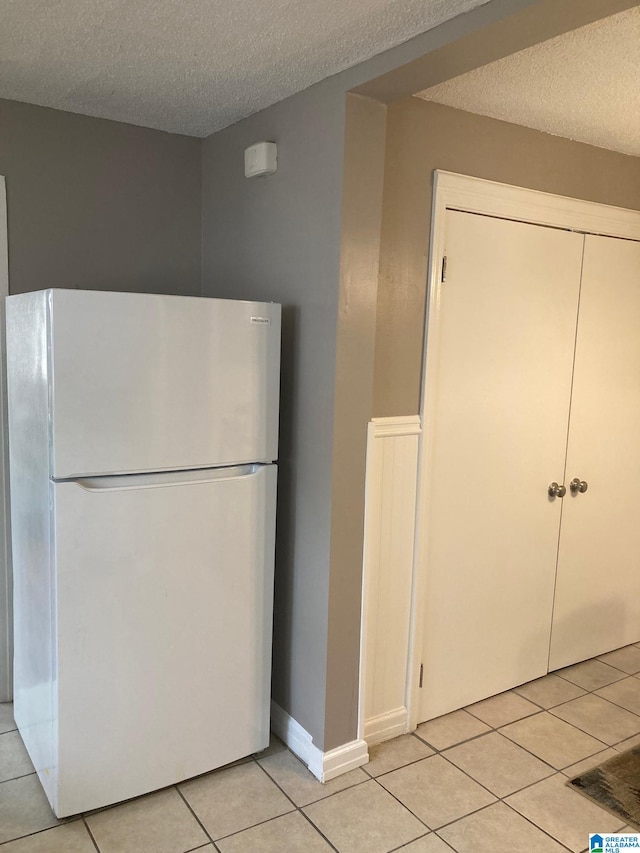 kitchen featuring a textured ceiling, light tile patterned floors, and white refrigerator