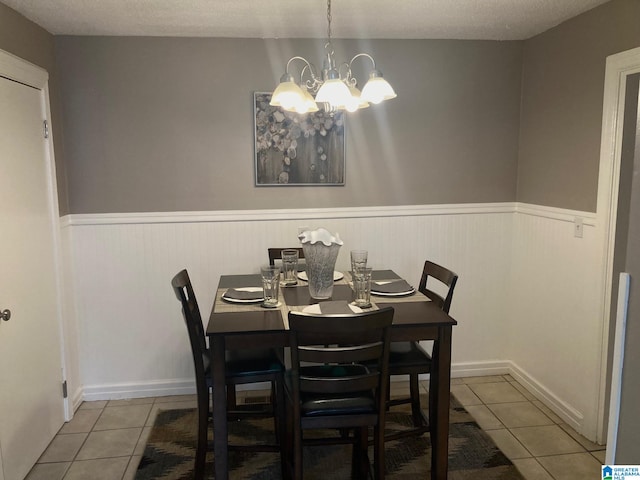 dining space with a textured ceiling, a chandelier, and light tile patterned floors