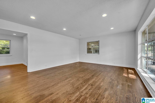 empty room with dark hardwood / wood-style floors and a textured ceiling