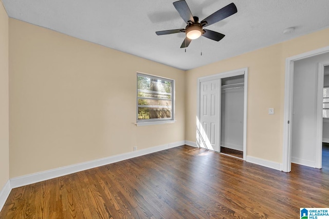 unfurnished bedroom with a textured ceiling, ceiling fan, a closet, and dark hardwood / wood-style flooring