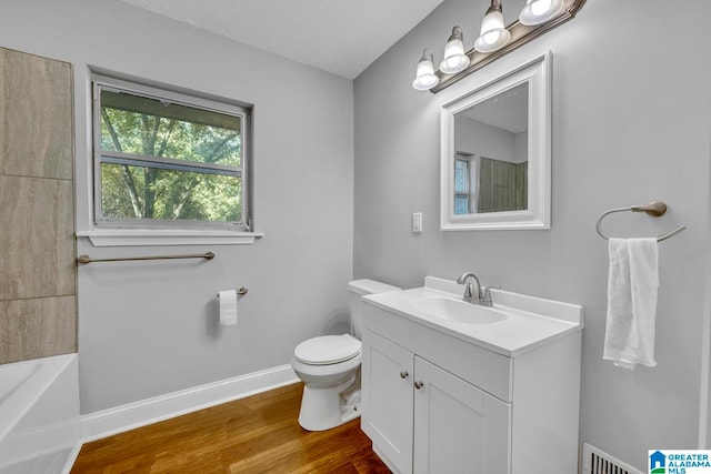 bathroom featuring a textured ceiling, wood-type flooring, vanity, and toilet