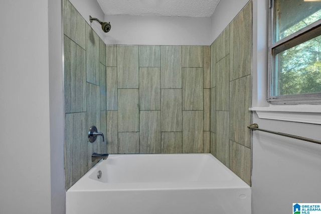 bathroom with tiled shower / bath and a textured ceiling