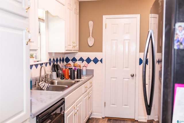 kitchen with black dishwasher, sink, white cabinets, stainless steel refrigerator, and dark hardwood / wood-style flooring