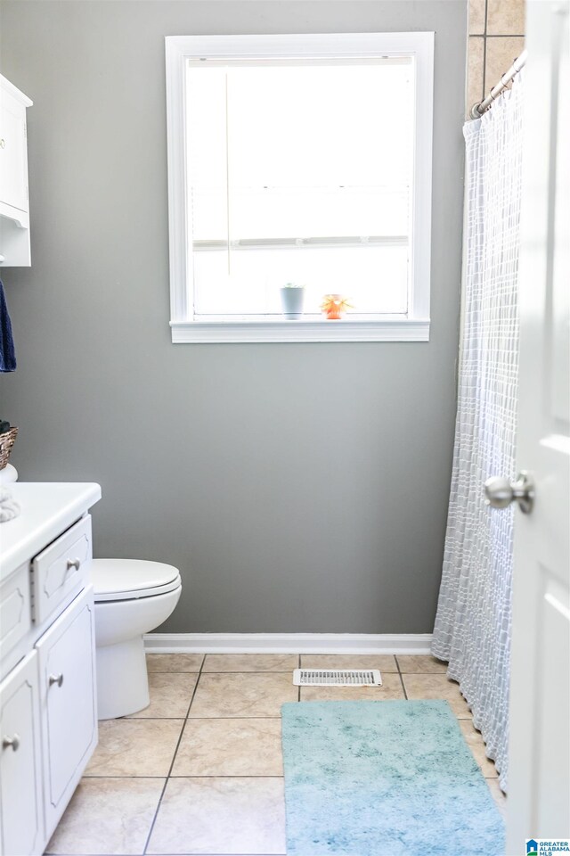 bathroom with a shower with shower curtain, vanity, toilet, and tile patterned floors