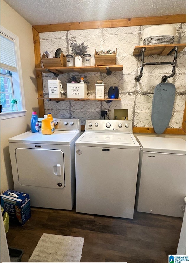 clothes washing area with dark wood-type flooring, a textured ceiling, and separate washer and dryer