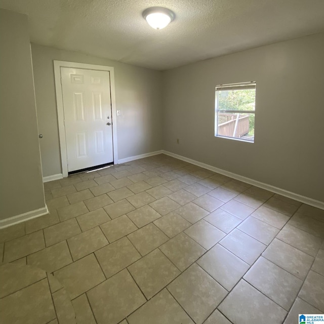 unfurnished room featuring a textured ceiling and light tile patterned flooring