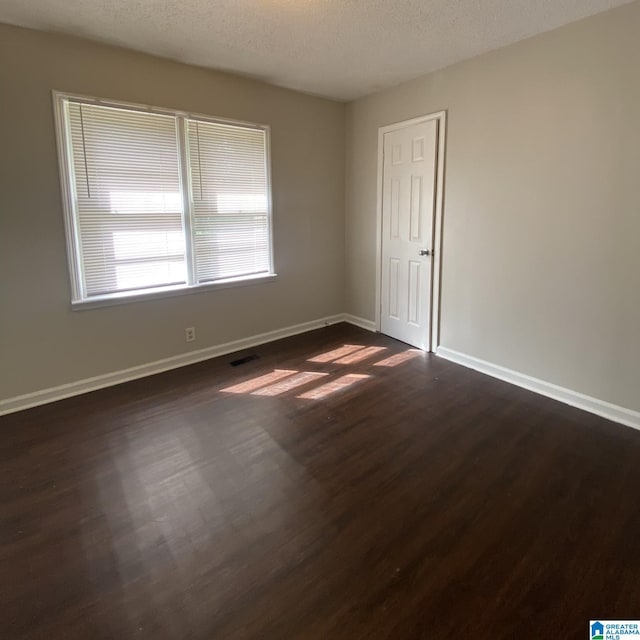 1121 Skyline Dr, Birmingham, AL 35214 - unfurnished room featuring dark wood-type flooring, a textured ceiling, baseboards, and visible vents
