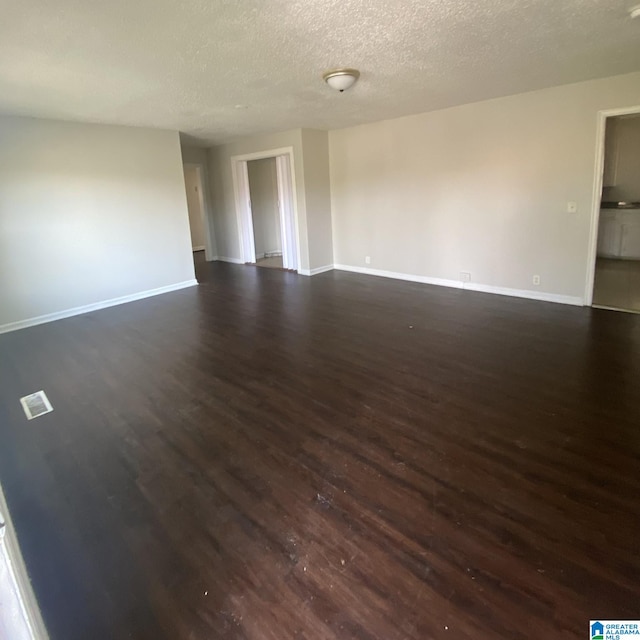 unfurnished room featuring a textured ceiling and dark hardwood / wood-style floors