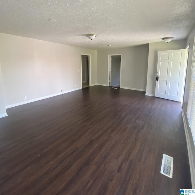 1121 Skyline Dr, Birmingham, AL 35214 - unfurnished living room with dark wood-type flooring, a textured ceiling, baseboards, and visible vents