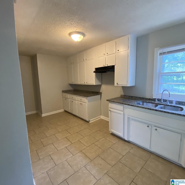 kitchen with a textured ceiling, sink, and white cabinetry