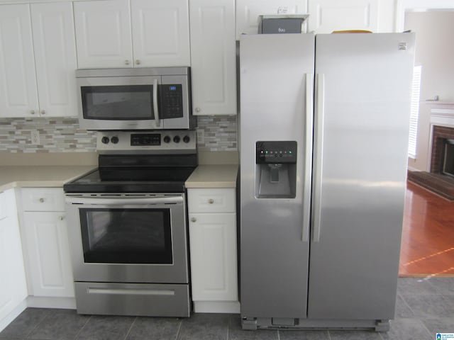 kitchen featuring dark tile patterned floors, white cabinets, appliances with stainless steel finishes, and tasteful backsplash