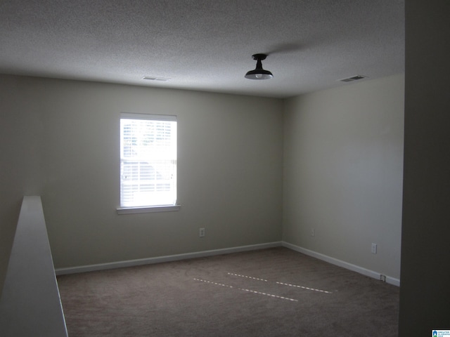 carpeted empty room featuring a textured ceiling