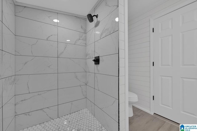 bathroom with hardwood / wood-style flooring, toilet, and tiled shower