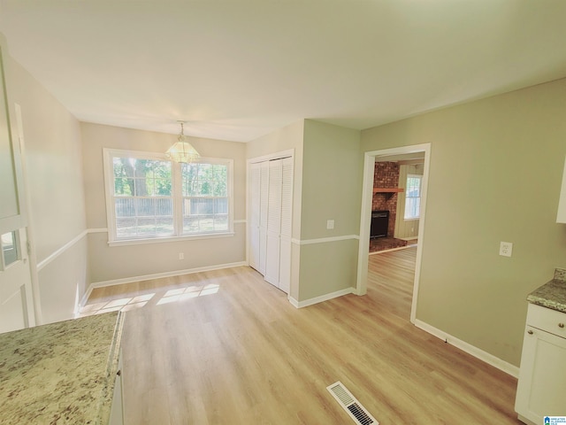 unfurnished dining area with light hardwood / wood-style flooring and a fireplace