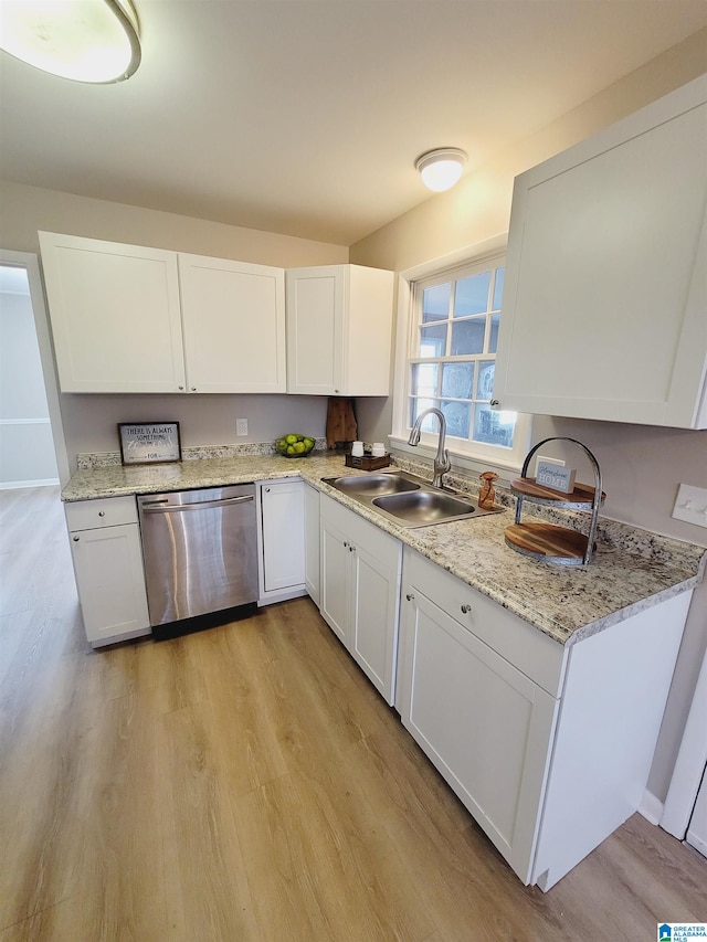 kitchen featuring light stone counters, white cabinets, sink, stainless steel dishwasher, and light wood-type flooring