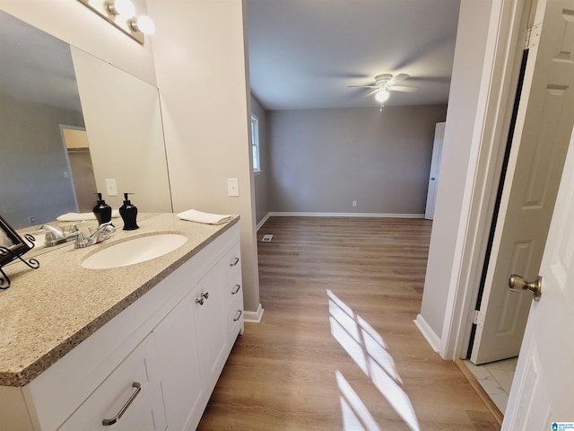 bathroom with ceiling fan, vanity, wood finished floors, and baseboards