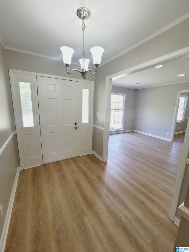 foyer entrance featuring a chandelier, light wood-style floors, baseboards, and ornamental molding