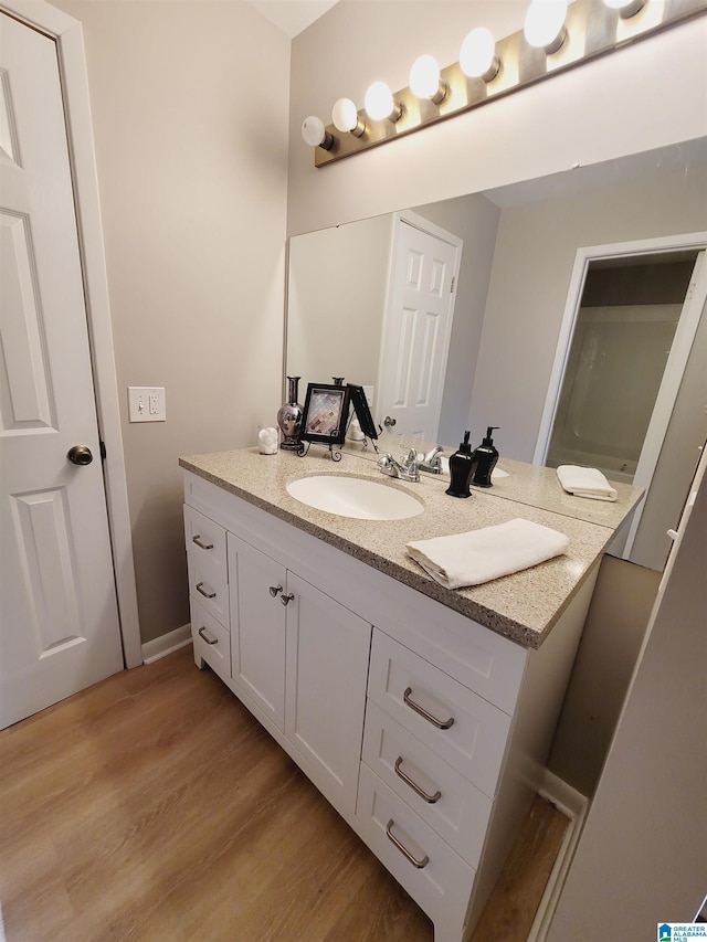 bathroom with wood finished floors, vanity, and baseboards