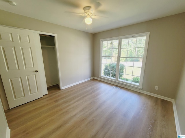 unfurnished bedroom with a closet, light wood-style floors, baseboards, and ceiling fan