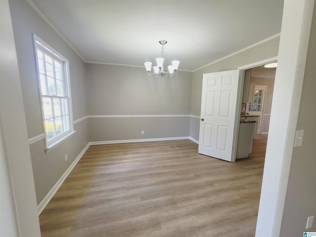 spare room with baseboards, light wood-type flooring, an inviting chandelier, and crown molding
