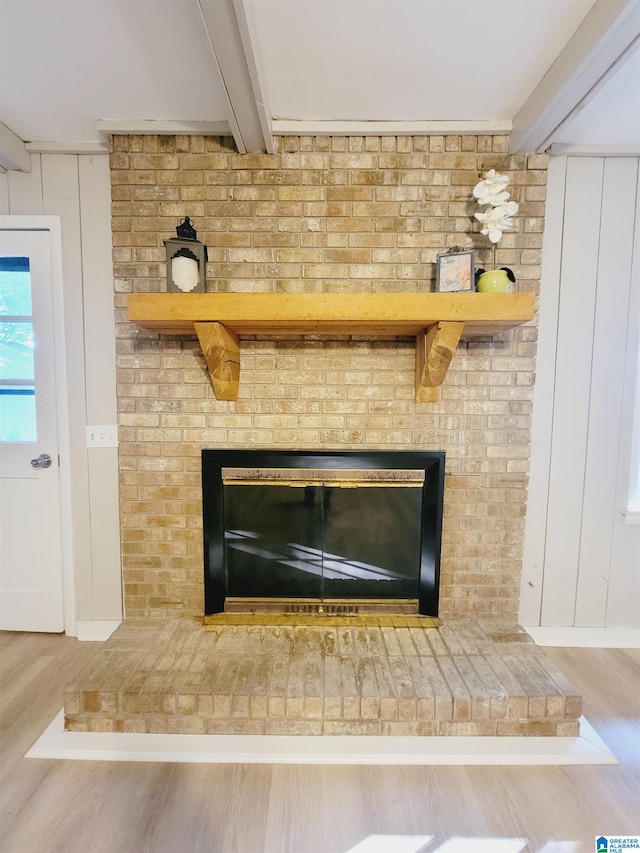 details with a brick fireplace, beamed ceiling, wood walls, and hardwood / wood-style floors