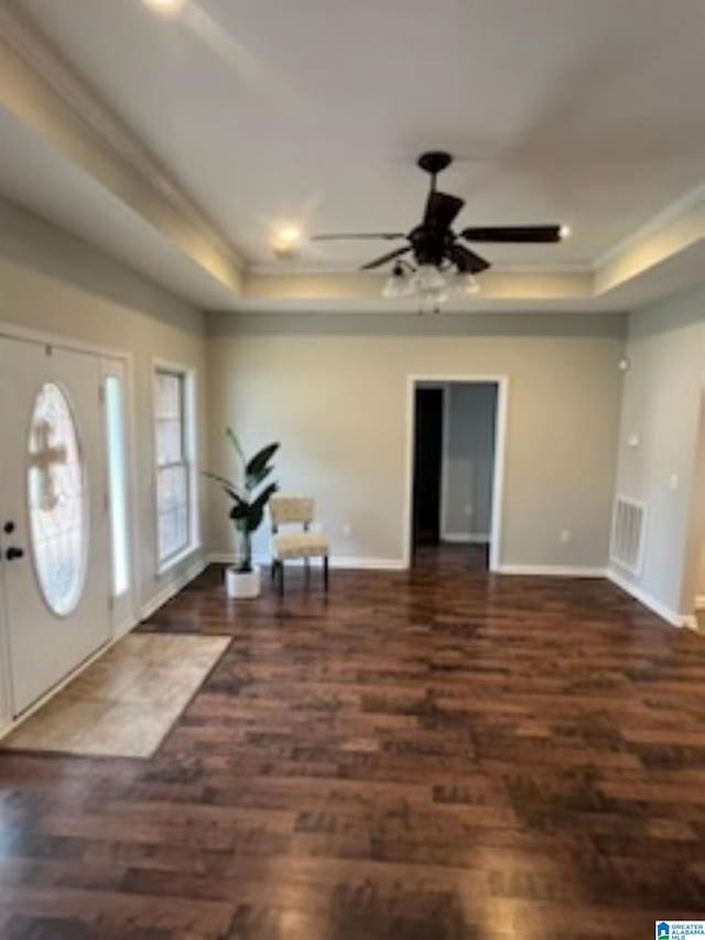 entrance foyer featuring ceiling fan, dark wood-type flooring, and a tray ceiling