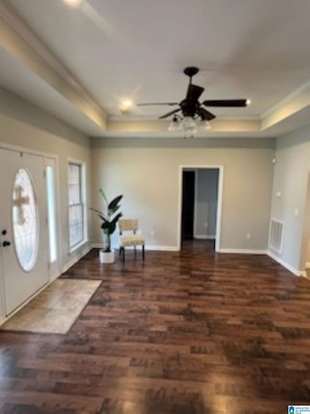 entrance foyer featuring dark hardwood / wood-style floors, ceiling fan, and a tray ceiling