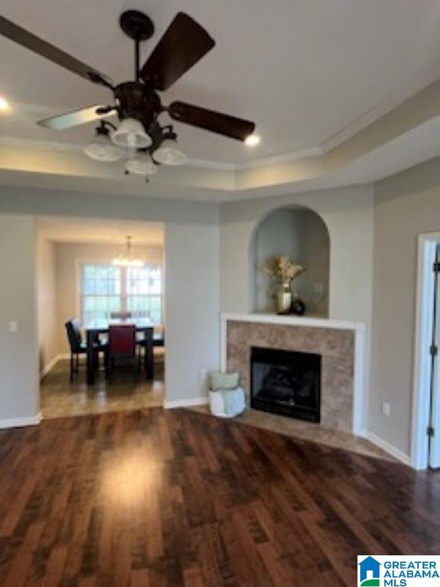 living room with dark hardwood / wood-style floors, ceiling fan, ornamental molding, and a tray ceiling