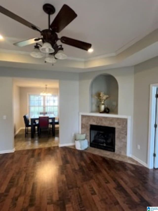 living room with a tray ceiling, dark hardwood / wood-style floors, ornamental molding, and ceiling fan