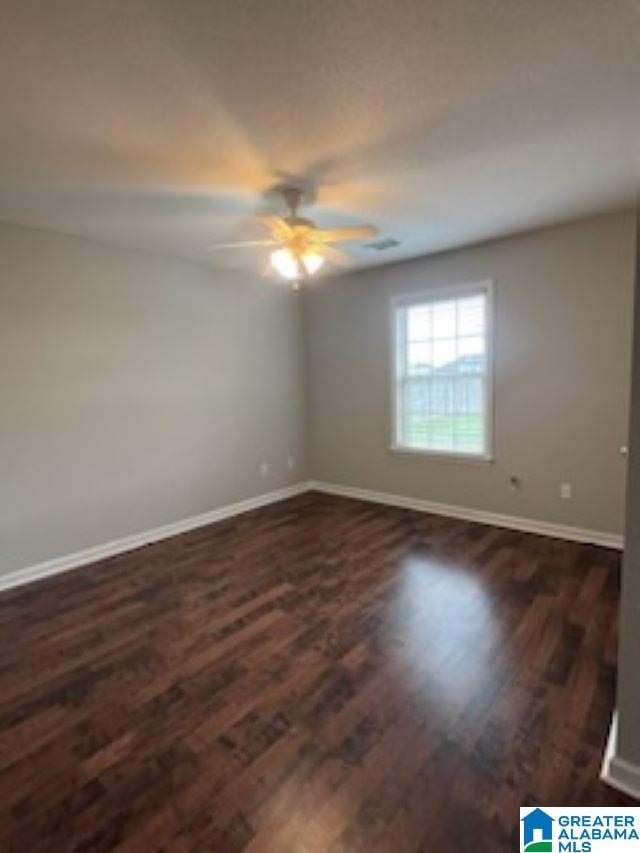 spare room with ceiling fan and dark wood-type flooring