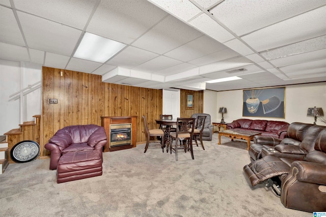 carpeted living room with a paneled ceiling and wood walls