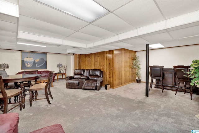 carpeted living room featuring wooden walls and a paneled ceiling