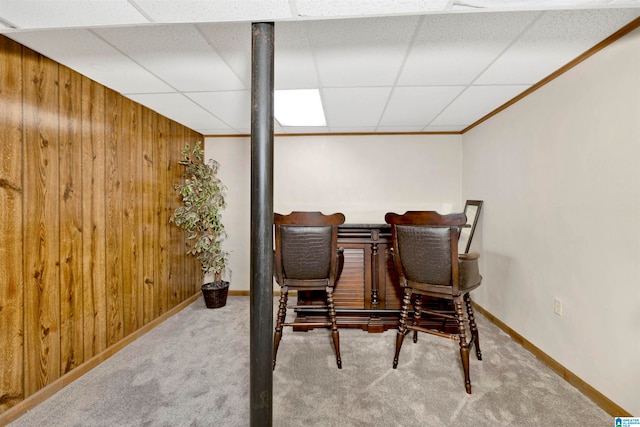 living area with carpet floors, a paneled ceiling, wood walls, and crown molding