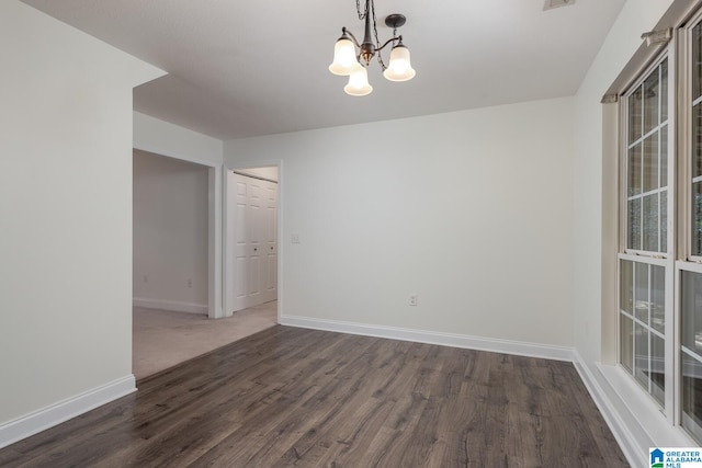 unfurnished room featuring an inviting chandelier and dark hardwood / wood-style flooring