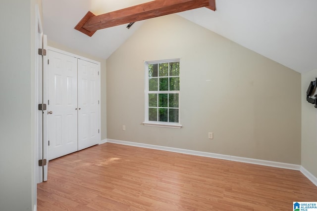 unfurnished bedroom featuring lofted ceiling with beams and light wood-type flooring