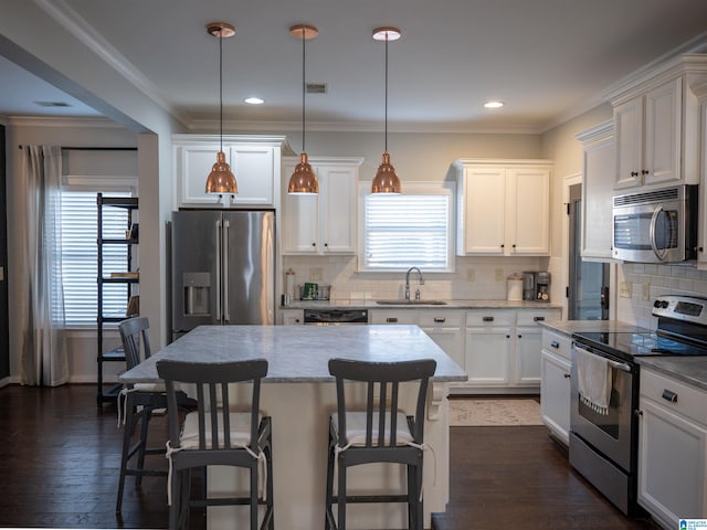 kitchen featuring decorative light fixtures, appliances with stainless steel finishes, dark hardwood / wood-style floors, and a center island