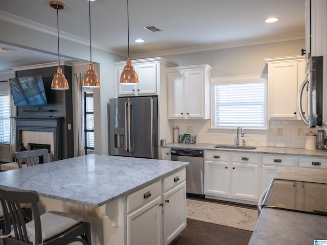 kitchen with white cabinets, hanging light fixtures, sink, appliances with stainless steel finishes, and a breakfast bar area