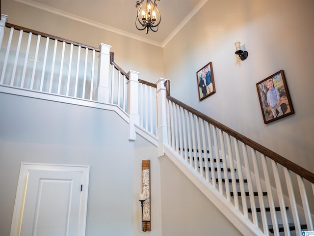 stairway featuring a notable chandelier, crown molding, and a towering ceiling