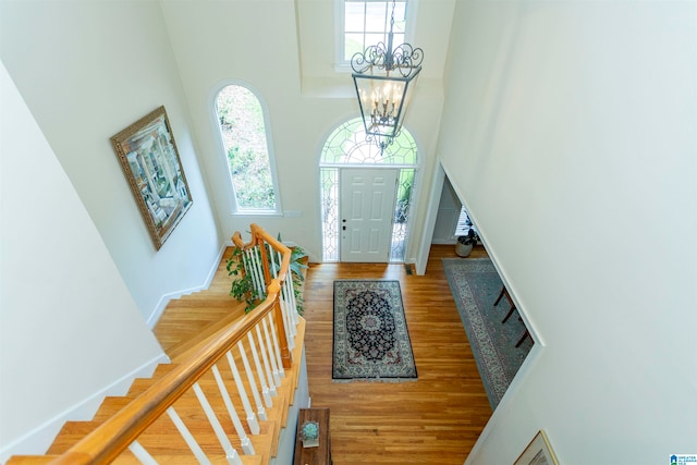 entryway featuring a high ceiling, hardwood / wood-style flooring, and a chandelier