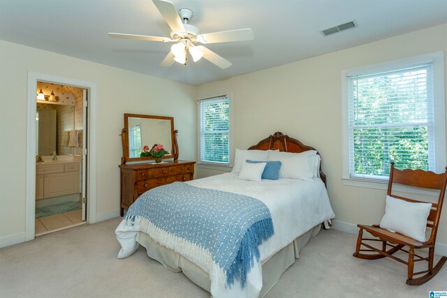 bedroom featuring light colored carpet, connected bathroom, and ceiling fan