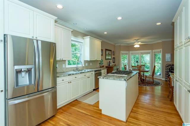 kitchen featuring light stone counters, white cabinetry, stainless steel appliances, a center island, and light hardwood / wood-style floors