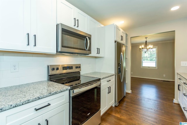 kitchen featuring dark hardwood / wood-style floors, stainless steel appliances, white cabinetry, a chandelier, and ornamental molding