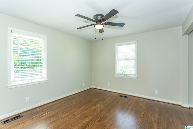 empty room with dark wood-type flooring, plenty of natural light, and ceiling fan