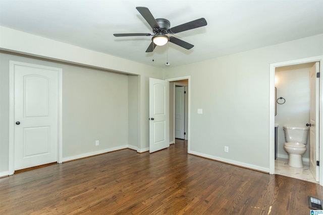 unfurnished bedroom featuring ceiling fan, ensuite bath, and dark hardwood / wood-style flooring