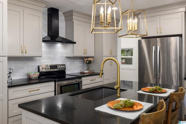 kitchen featuring pendant lighting, backsplash, wall chimney range hood, white cabinetry, and appliances with stainless steel finishes