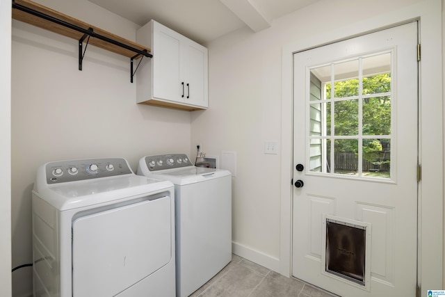 clothes washing area featuring separate washer and dryer, cabinets, and light tile patterned floors