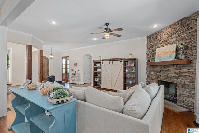 living room featuring dark wood-type flooring, crown molding, a barn door, and a fireplace