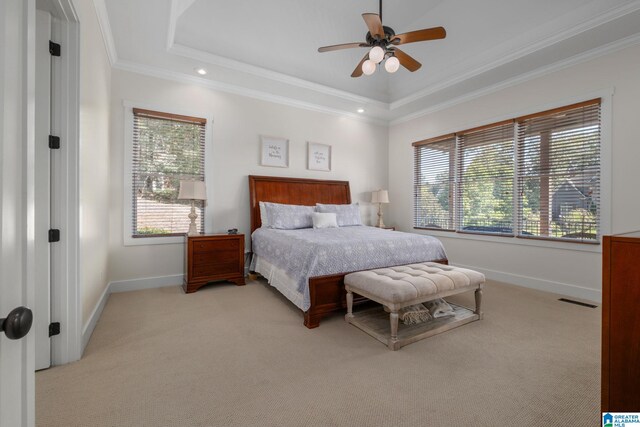 bedroom with a tray ceiling, light colored carpet, multiple windows, and ceiling fan