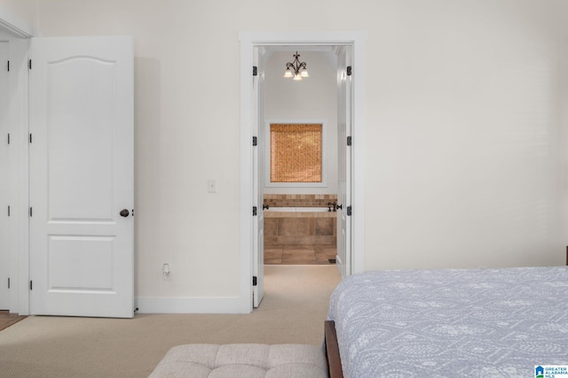 bedroom with a chandelier, ensuite bathroom, and light carpet