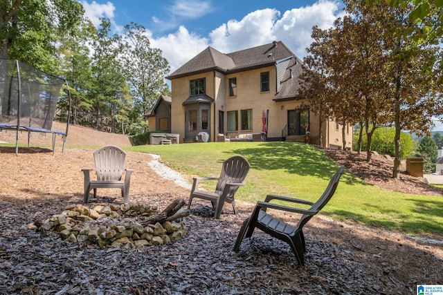 rear view of house featuring a trampoline and a lawn